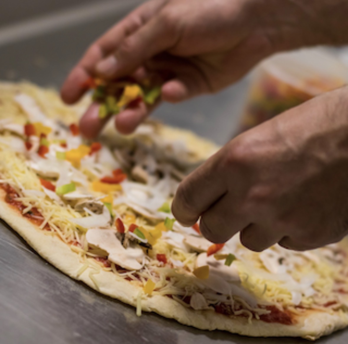 Garniture d'une pizza à la main dans le laboratoire
